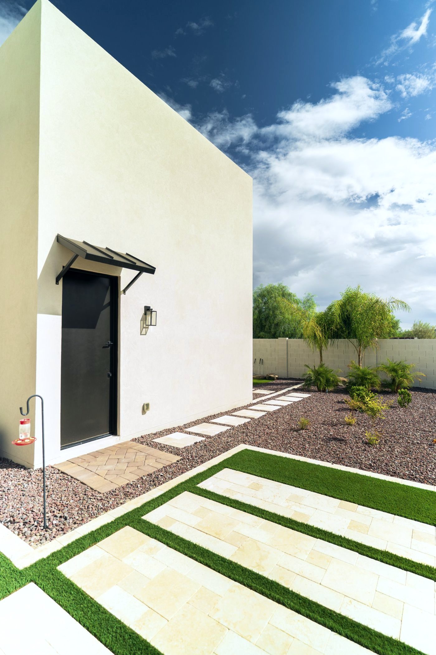 Travertine and turf strip patio beside a modern casita