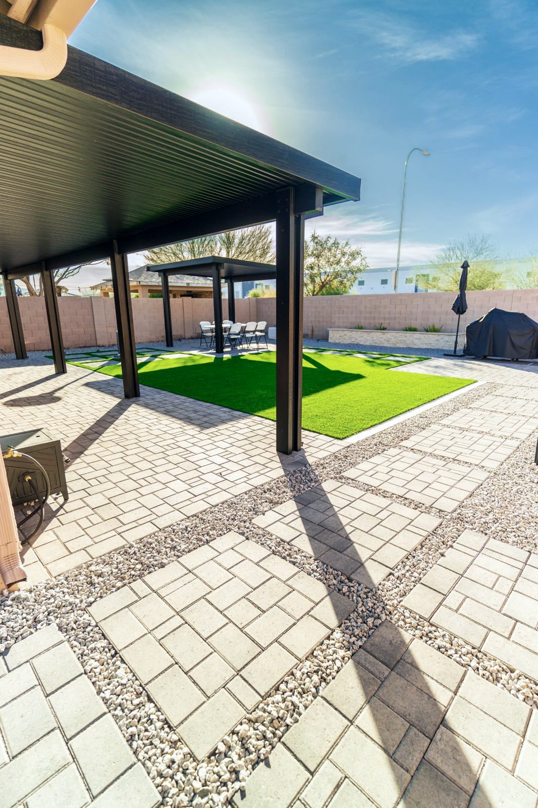 Solid-roof pergolas over a paver patio and turf