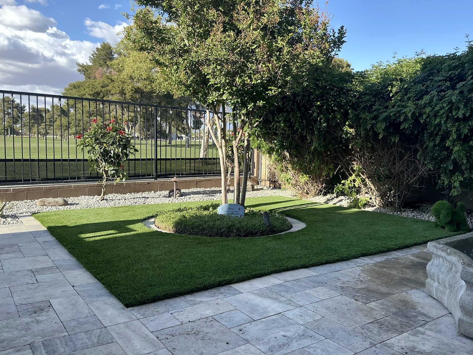Turf courtyard around a tree ring beside a travertine patio